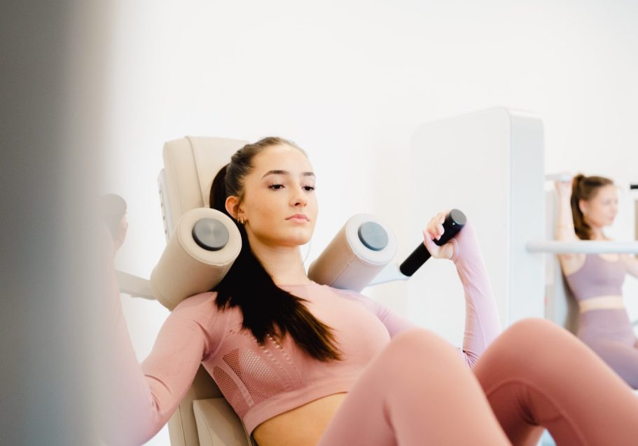 Junge Frau trainiert in einem Fitnessstudio an einem Kraftgerät.