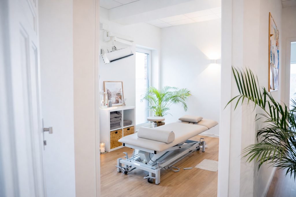 Heller, minimalistischer Raum mit einem Behandlungstisch und Pflanzen.