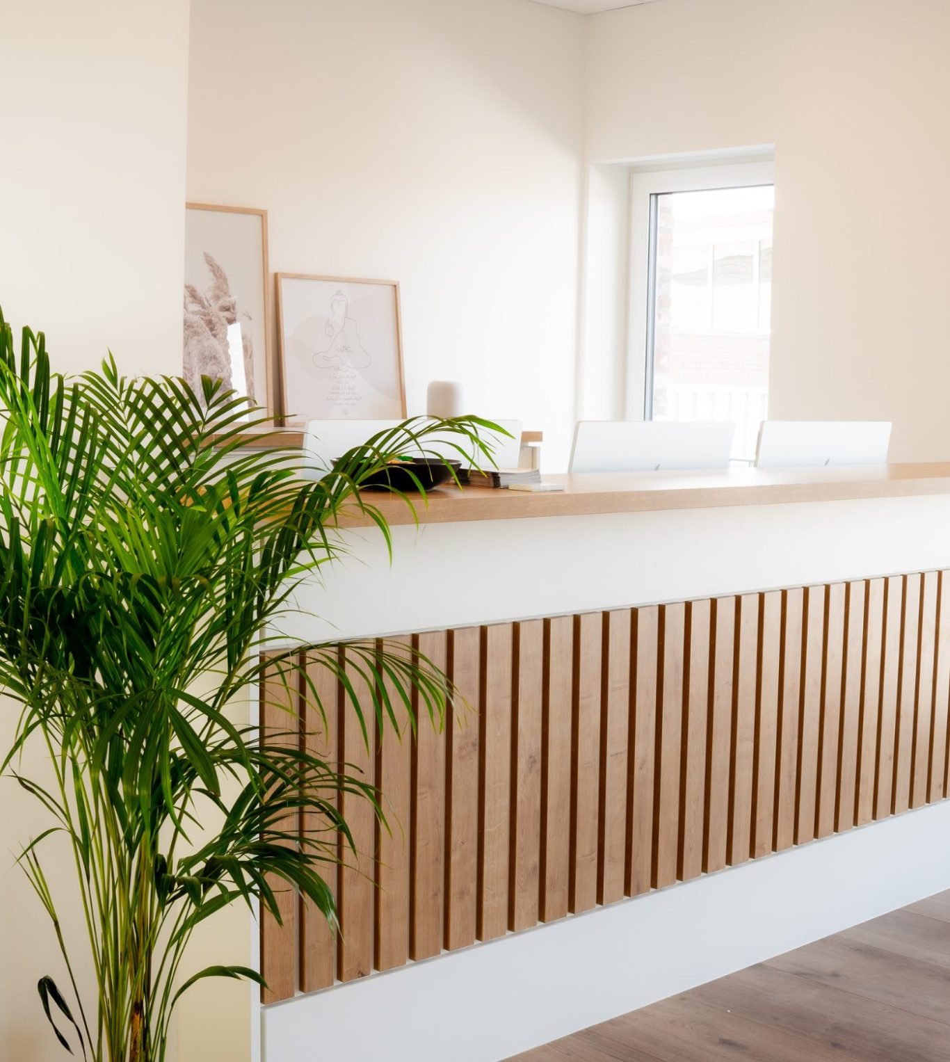 Moderne Empfangstheke mit Holzverkleidung und Pflanzen im Hintergrund.